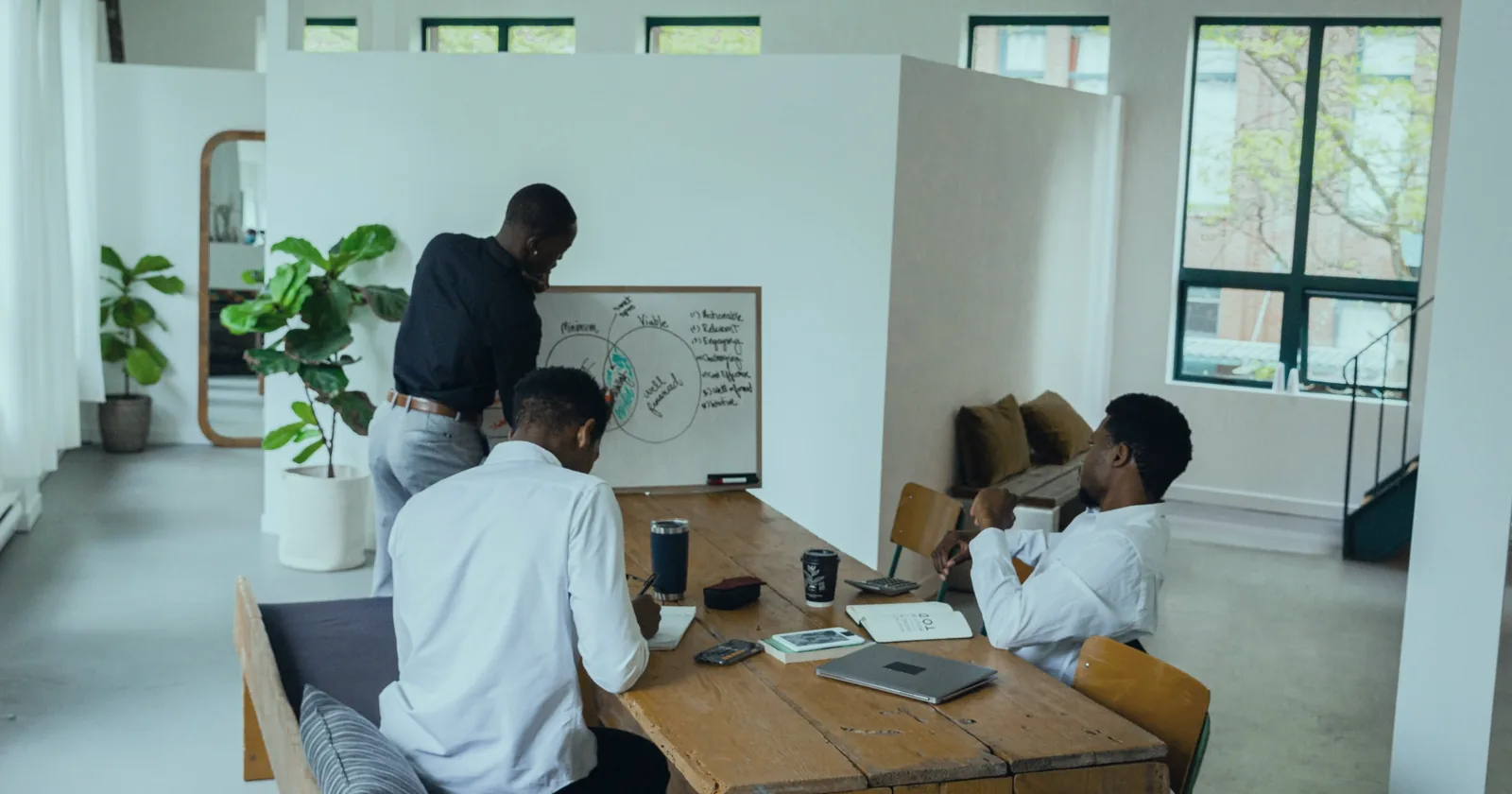 Colleagues mapping a process on a whiteboard in a bright open-plan office