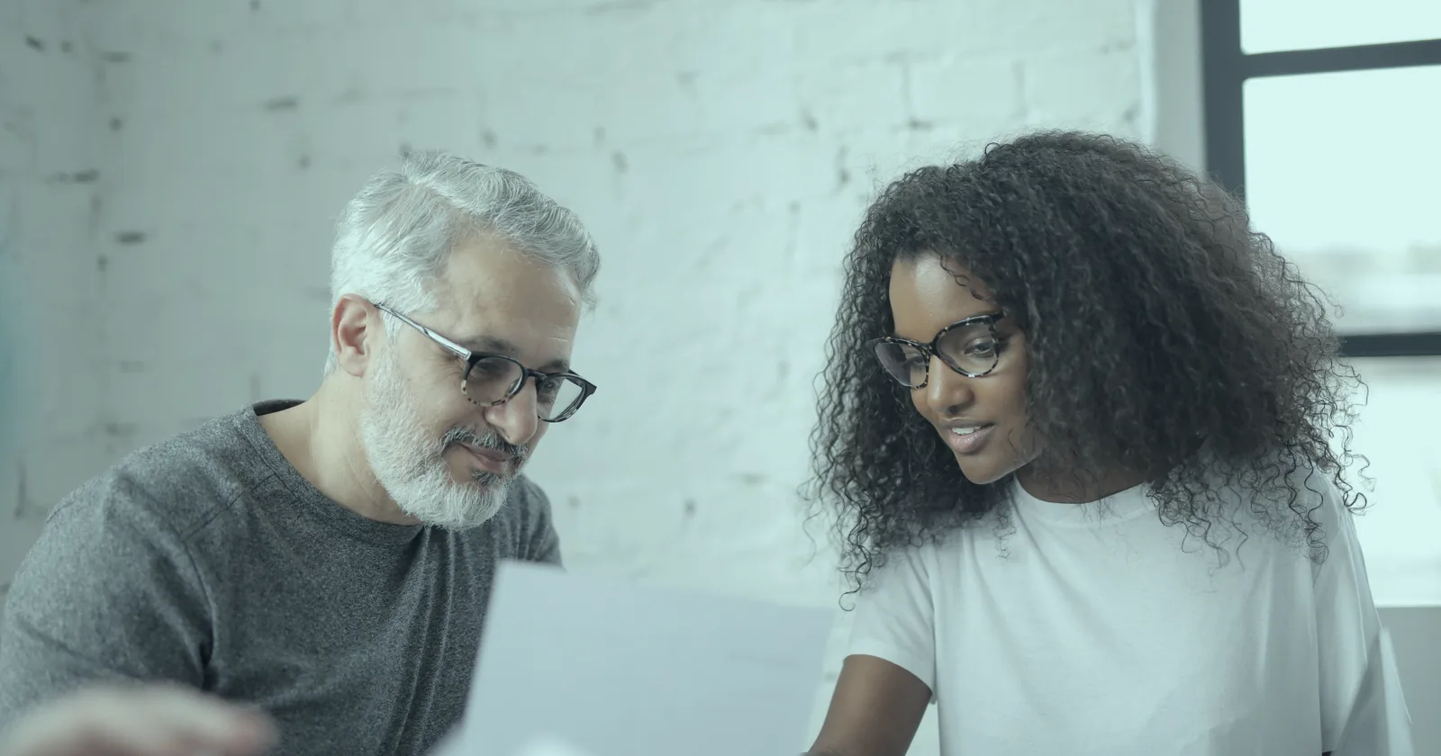 A manager and a colleague discussing a document together in an office